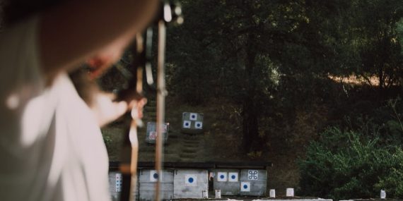 Focused archer aims at colorful targets in an outdoor forest range.